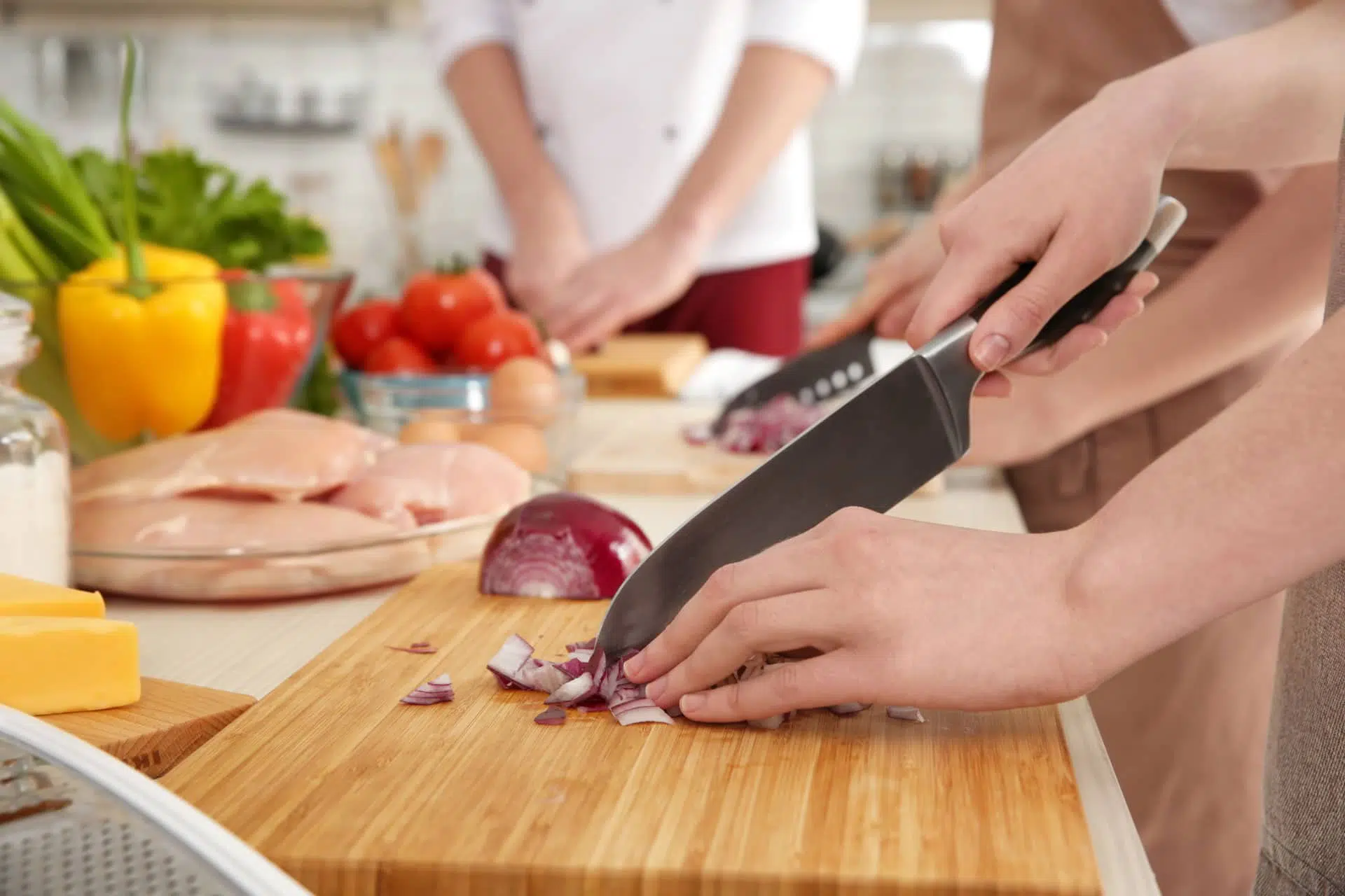 Des gens coupent des aliments sur des planches à découper sur le comptoir pour préparer le repas