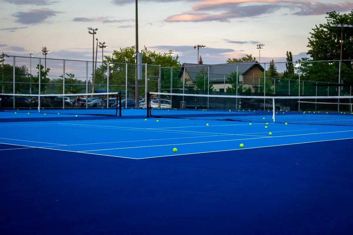 Terrains de tennis de couleur bleu avec des balles de tennis au sol à la fin d'une belle journée d'été