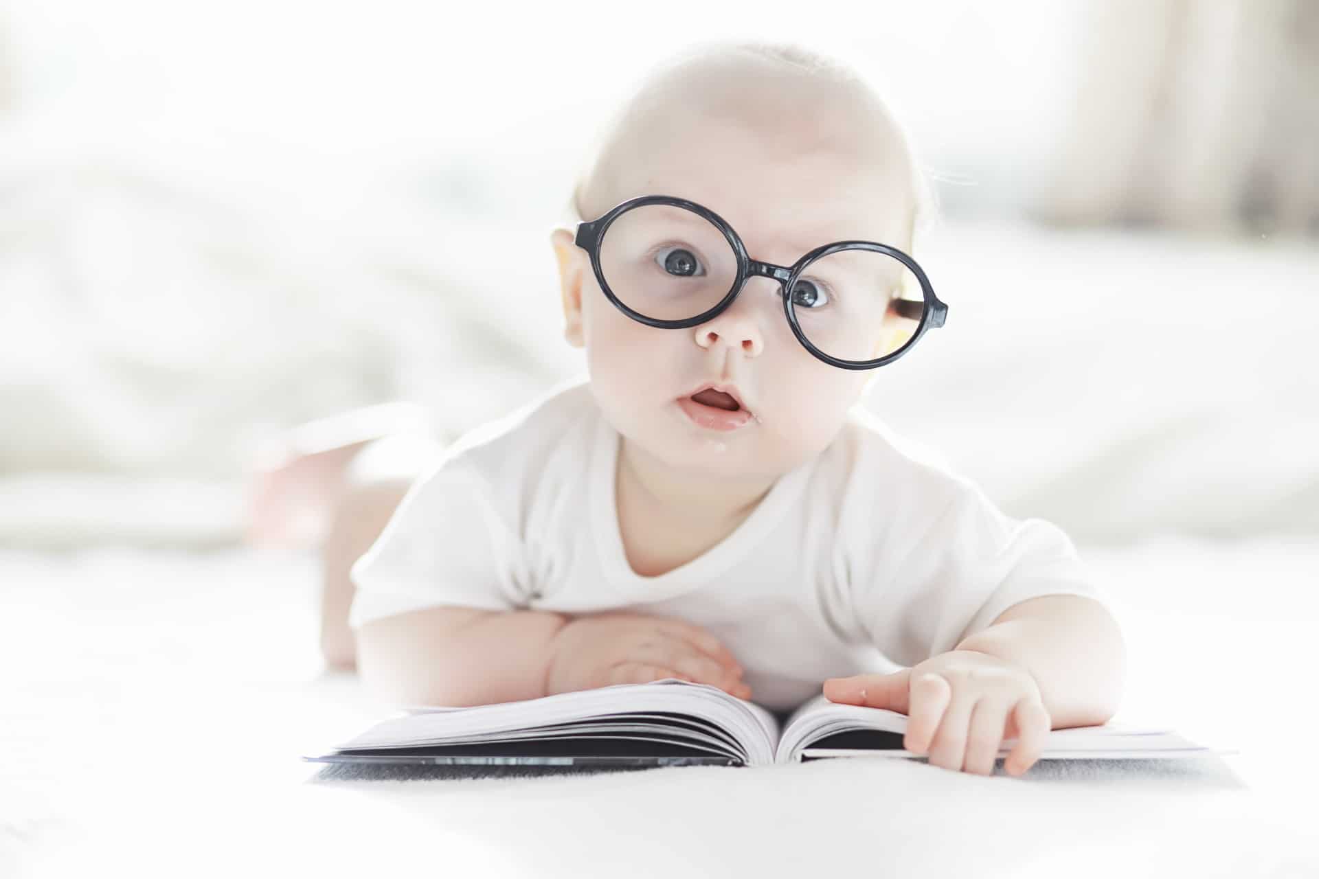 Bébé avec lunette a plat ventre sur un livre