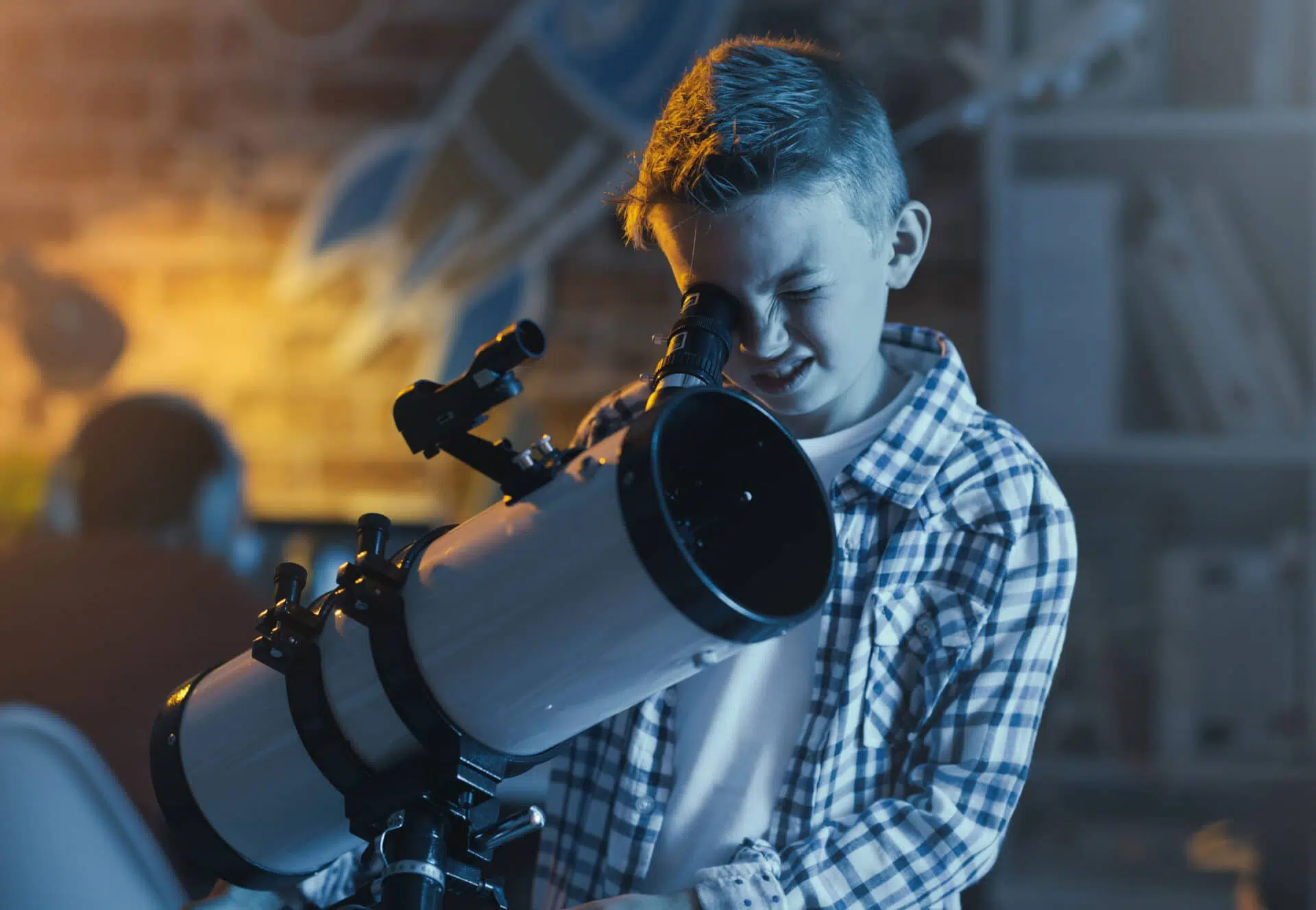 Jeune garçon qui regarde dans un télescope en soirée.