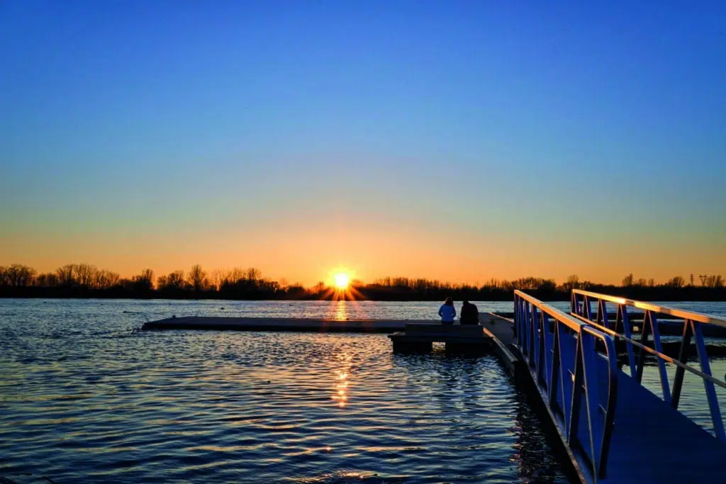 Un couple admirant le coucher du soleil sur le fleuve