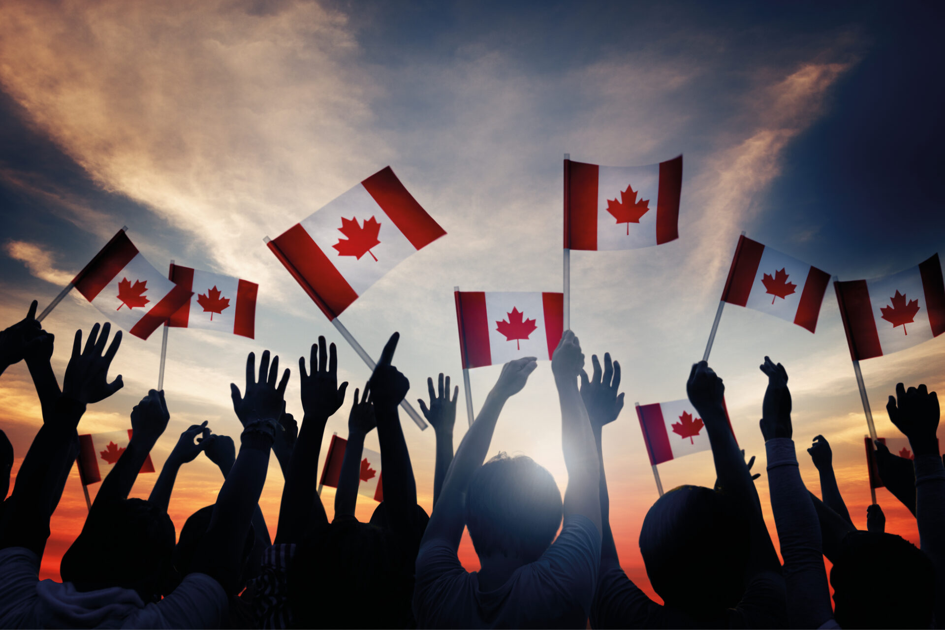 Foule à bras levés au ciel tenant des drapeaux du Canada