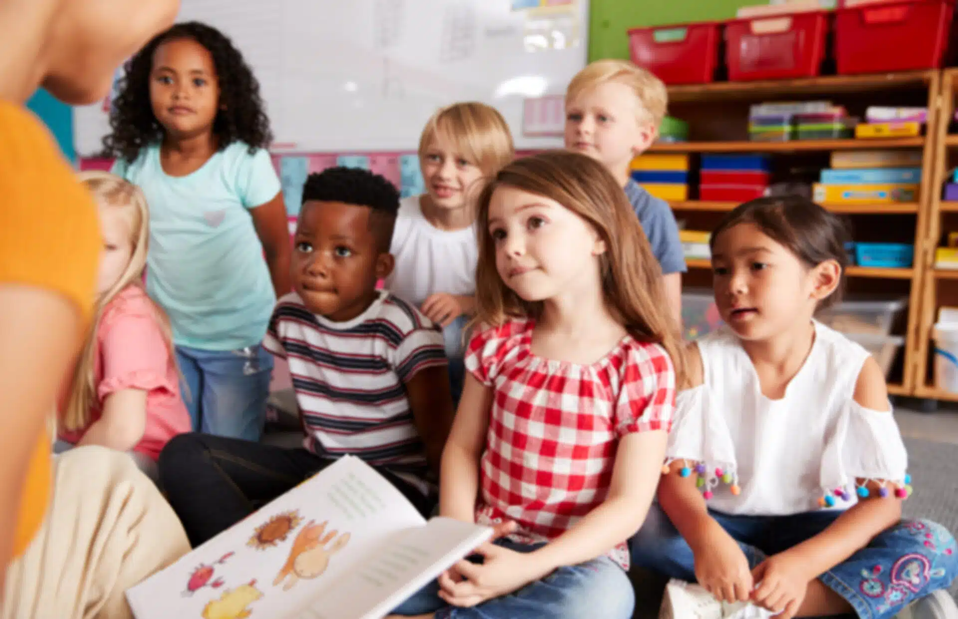 Enfants assis par terre qui écoutent une personne lire une histoire