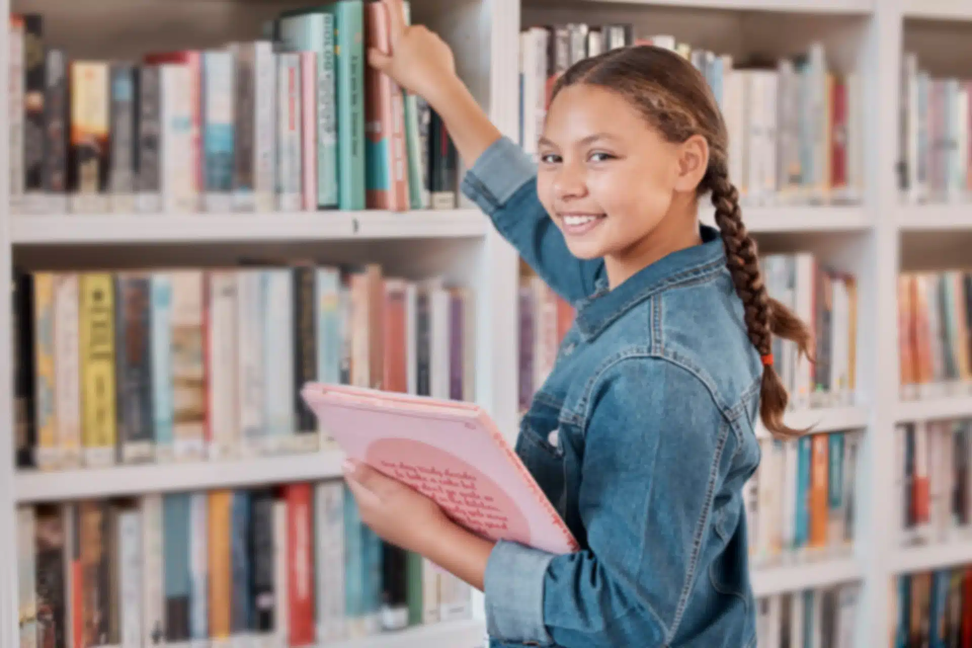 Jeune fille métissée avec des tresses qui place des livres dans une bilbiothèque